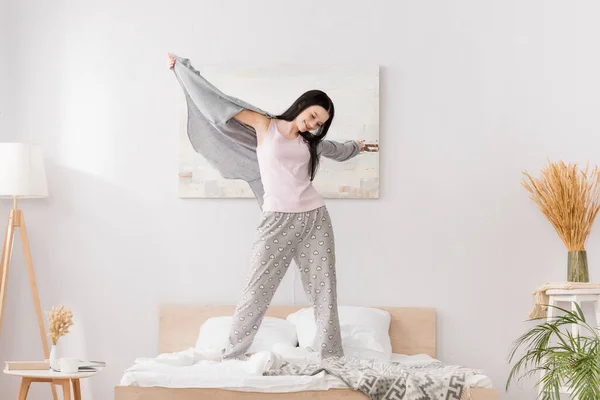 Full length of happy woman with vitiligo with outstretched hands standing on bed — Stock Photo