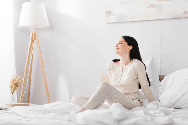Весела молода жінка з вітіліго сидить на ліжку вдома — стокове фото