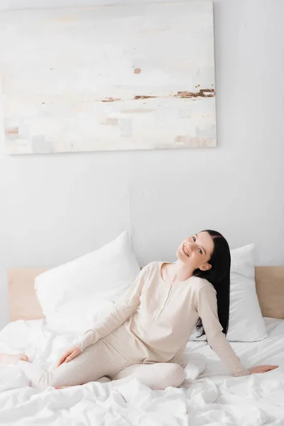 Pleased young woman with vitiligo sitting on bed — Stock Photo