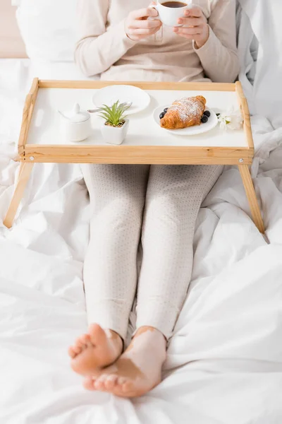 Cropped view of woman with vitiligo holding cup near breakfast on tray — Stock Photo