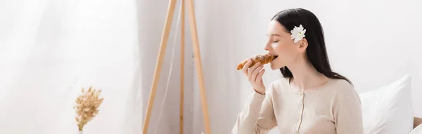 Молодая брюнетка женщина с витилиго едят круассан, баннер — стоковое фото