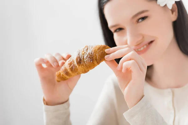 Croissant in hands of happy woman with vitiligo on blurred background — Stock Photo