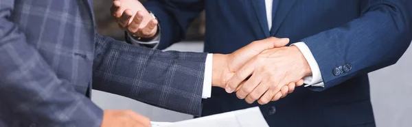 Vista recortada de hombres de negocios dándose la mano, pancarta - foto de stock