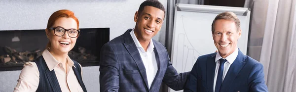 Happy multicultural businesspeople looking at camera in meeting room, banner — Stock Photo