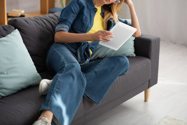 Обрезанный вид молодой женщины с цифровым планшетом на диване дома на размытом фоне — стоковое фото