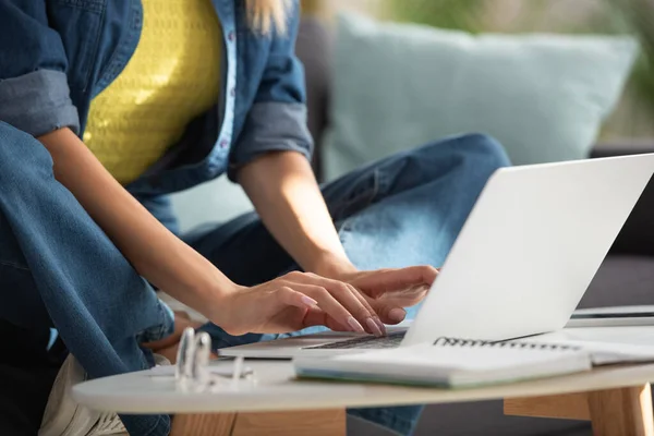 Vue recadrée de la jeune femme tapant sur ordinateur portable au premier plan flou à la maison — Photo de stock