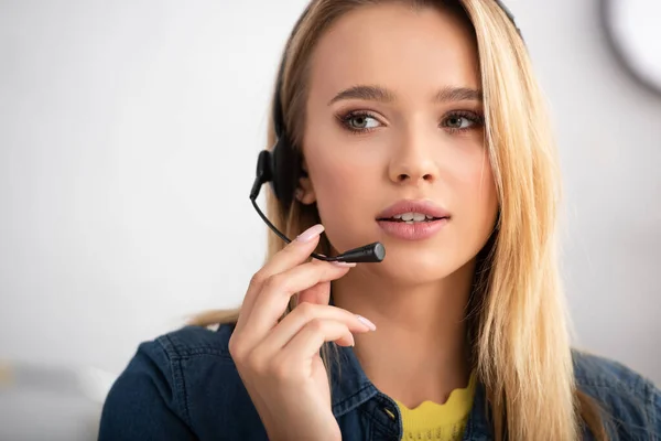 Portrait of young blonde woman in headset looking away on blurred background — Stock Photo