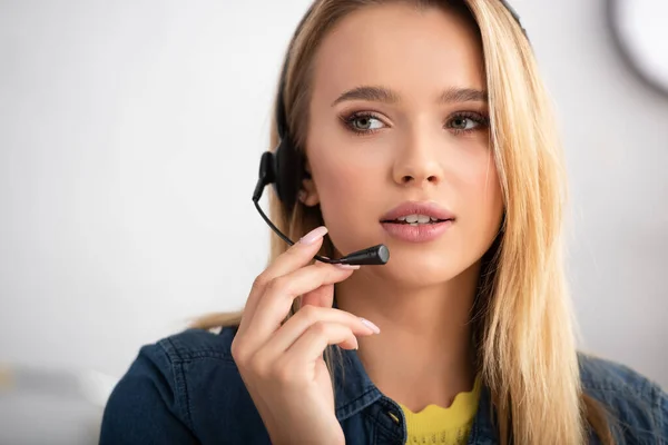 Portrait de jeune femme blonde en casque regardant loin sur fond flou — Photo de stock