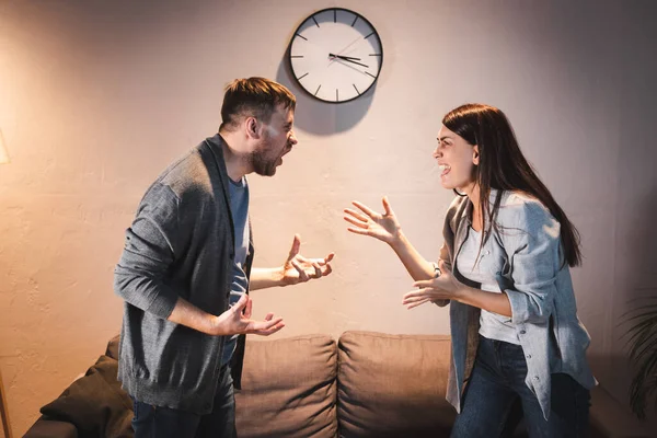 Vista lateral de borrachos, adictos al alcohol marido y la esposa peleando en casa - foto de stock