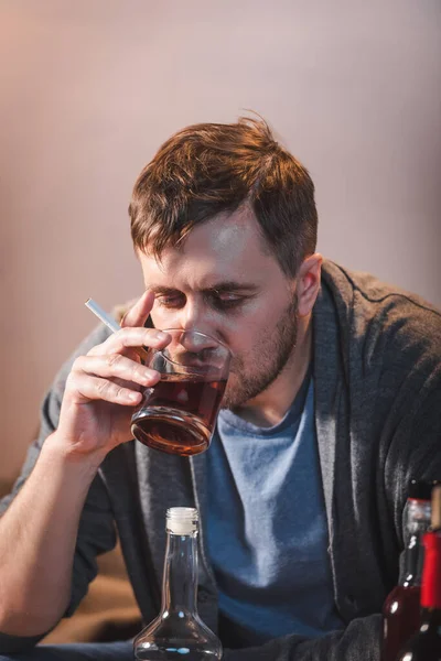 Einsamer Mann trinkt Whisky, während er allein zu Hause sitzt — Stockfoto