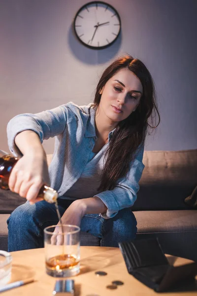 Betrunkene Frau gießt Whiskey in Glas auf verschwommenem Vordergrund — Stockfoto