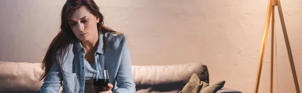 Mujer frustrada sentada con una copa de vino tinto en casa sola, pancarta - foto de stock