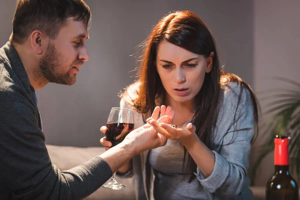 Man giving wedding ring to drunk wife holding glass of wine — Stock Photo