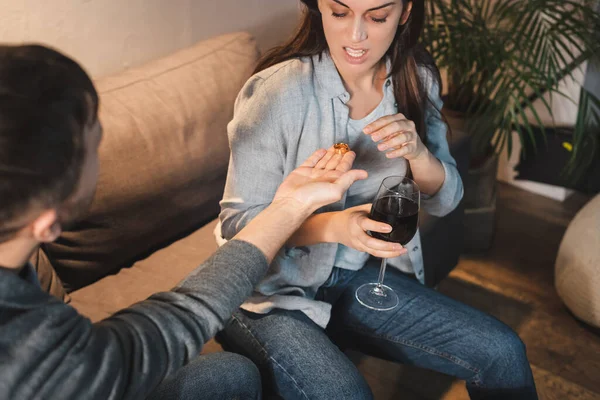 Husband giving wedding ring to drunk wife holding glass of wine, blurred foreground — Stock Photo