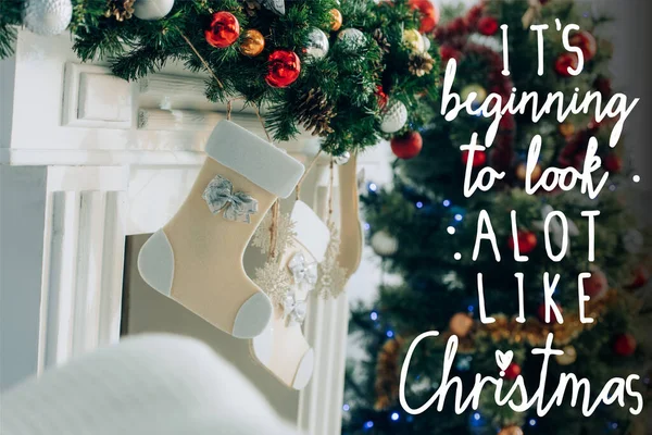 Stocking on decorated spruce branch near fireplace and its beginning to look a lot like christmas lettering — Stock Photo