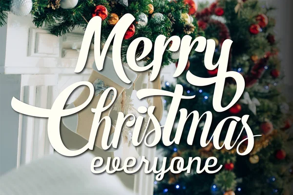 Stocking on decorated spruce branch near fireplace and merry christmas everyone lettering — Stock Photo