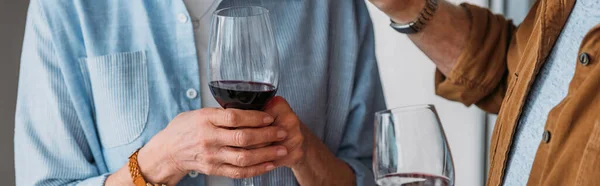 Vista recortada de pareja de ancianos sosteniendo copas de vino, pancarta - foto de stock