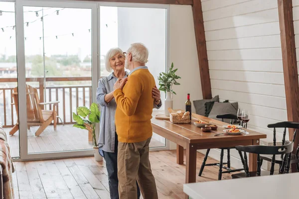 Glückliches Seniorenpaar tanzt am Tisch mit Abendessen zu Hause — Stockfoto