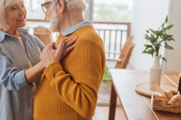 Felice moglie anziana guardando il marito durante la danza su sfondo sfocato a casa — Foto stock