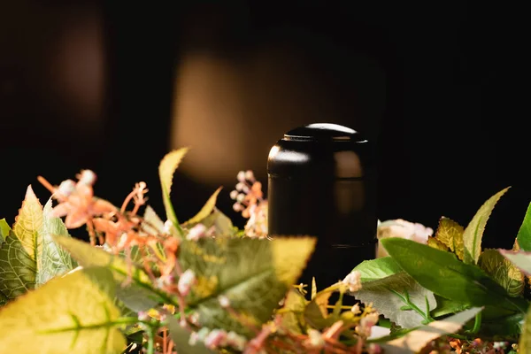 Bouquet e urna con cenere su sfondo nero, concetto funerario — Foto stock