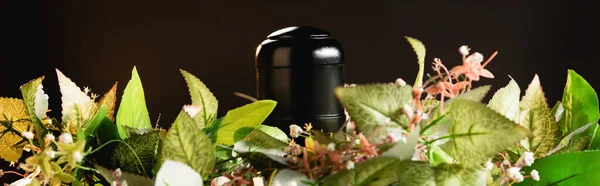 Bouquet and urn with ashes on black background, funeral concept, banner — Stock Photo