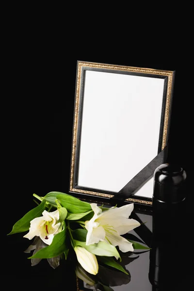 Flowers, mirror with black ribbon and urn with ashes on black background, funeral concept — Stock Photo