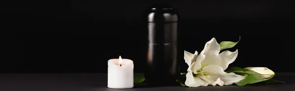 Lily, candle and urn with ashes on black background, funeral concept, banner — Stock Photo