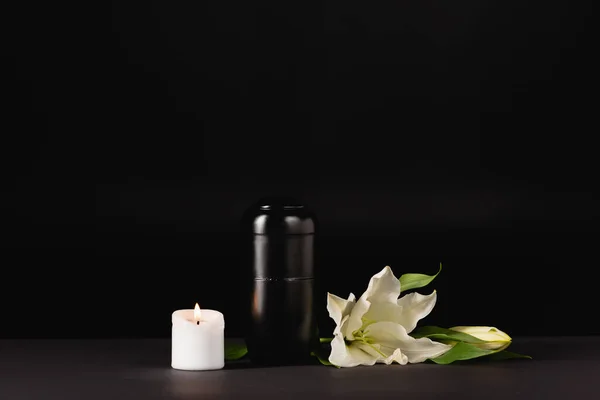 Lilie, Kerze und Urne mit Asche auf schwarzem Hintergrund, Bestattungskonzept — Stockfoto