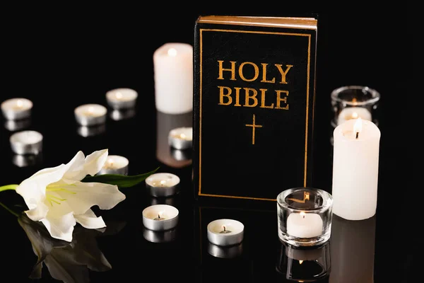 Lily, candles and holy bible on black background, funeral concept — Stock Photo