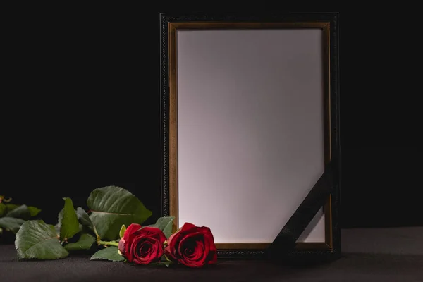Dos rosas rojas y espejo con cinta sobre fondo negro, concepto funerario - foto de stock
