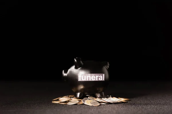 Sparschwein mit Münzen auf schwarzem Hintergrund, Bestattungskonzept — Stockfoto