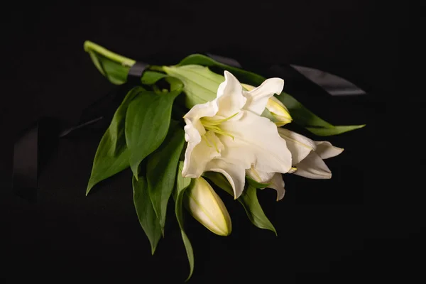 Lily bouquet and ribbon on black background, funeral concept — Stock Photo