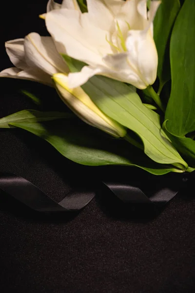 Close-up de lírio buquê e fita sobre fundo preto, conceito funeral — Fotografia de Stock