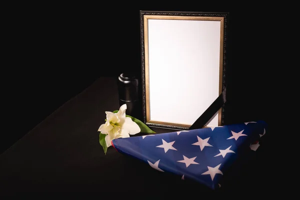 Lírio, espelho, cinzas e bandeira americana em fundo preto, conceito funeral — Fotografia de Stock