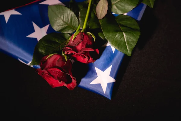 Rote Rosen und amerikanische Flagge auf schwarzem Hintergrund, Bestattungskonzept — Stockfoto