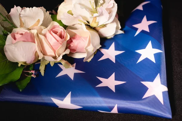 Ramo de rosas y bandera americana sobre fondo negro, concepto funerario - foto de stock
