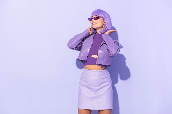 Sonriente mujer joven vestida con estilo de muñeca sobre fondo de color violeta - foto de stock