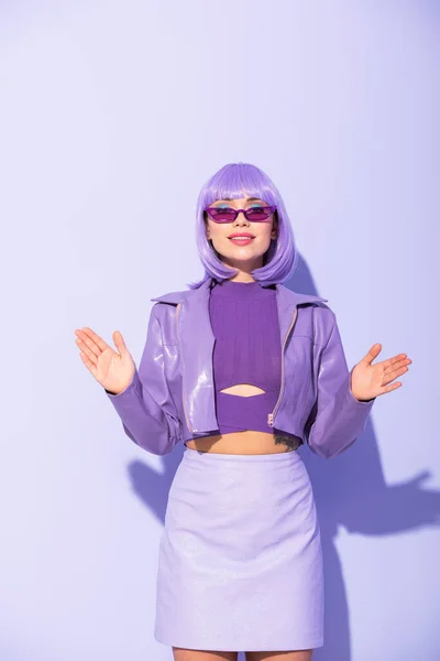 Sonriente mujer joven vestida con estilo de muñeca sobre fondo de color violeta - foto de stock
