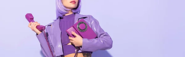 Обрізаний вид на молоду жінку, одягнену в ляльковий стиль з ретро телефоном на фіолетовому барвистому фоні — стокове фото