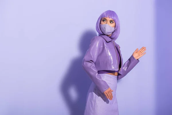 Jovem mulher vestida em estilo boneca em máscara médica em fundo colorido violeta — Fotografia de Stock