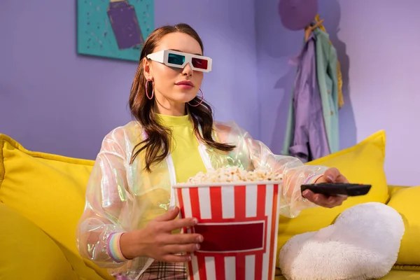 Junge Frau posiert als Puppe mit Popcorn und Fernbedienung in 3D-Brille auf gelbem Sofa — Stockfoto