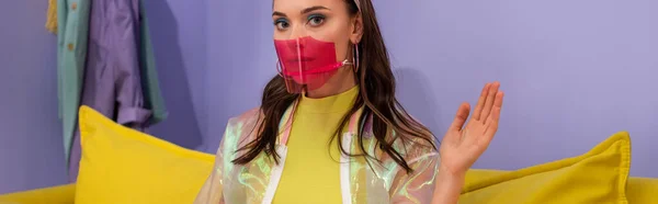 Young woman in medical mask posing as doll on yellow couch, banner — Stock Photo