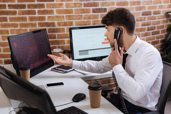 Geschäftsmann telefoniert und zeigt auf Computer mit Finanzkursen — Stockfoto