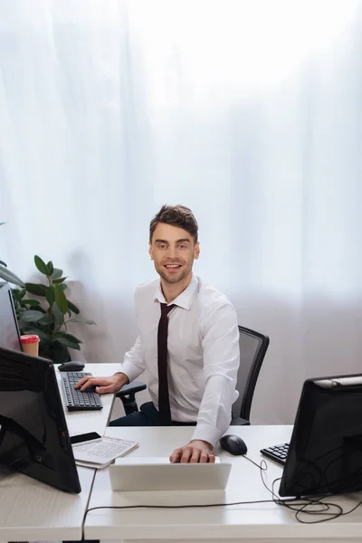 Homme d'affaires souriant utilisant des ordinateurs tout en vérifiant le marché financier au bureau — Photo de stock