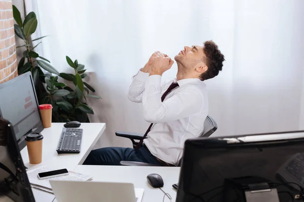 Young businessman showing yes gesture near devices, coffee to go and newspaper on blurred foreground — Stock Photo