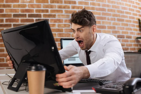 Uomo d'affari pazzo che tiene il monitor del computer in primo piano sfocato mentre controlla il mercato finanziario in carica — Foto stock