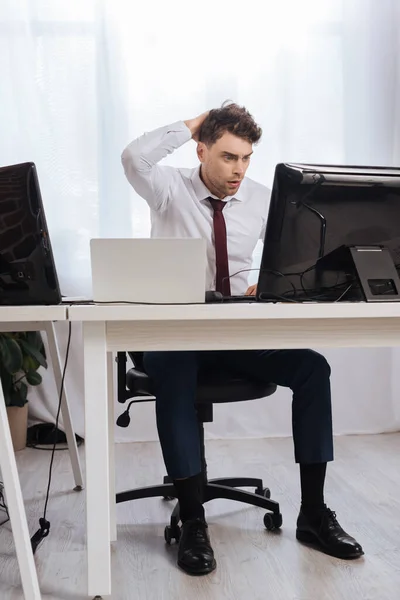 Worried businessman looking at computer while checking finance courses in office — Stock Photo