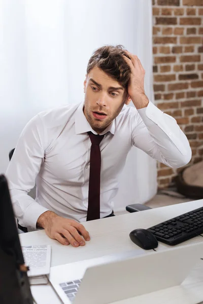 Upset businessman sitting near computers while analyzing finance market in office — Stock Photo