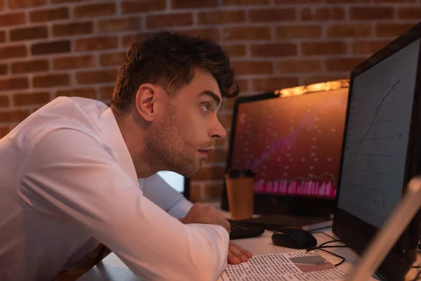 Businessman looking at graph on computer near newspaper in evening — Stock Photo