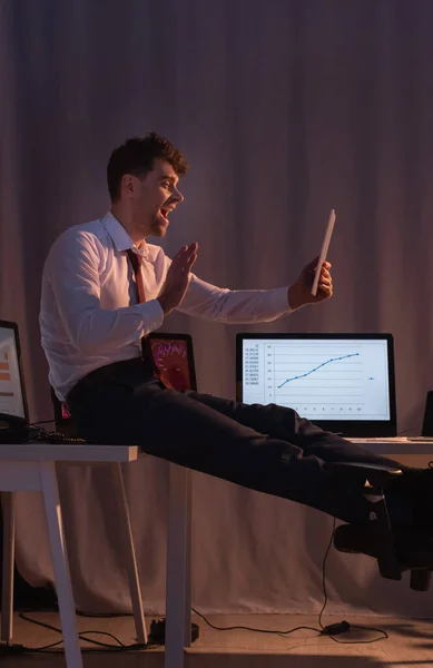 Cheerful businessman having video call on digital tablet near computers in office — Stock Photo